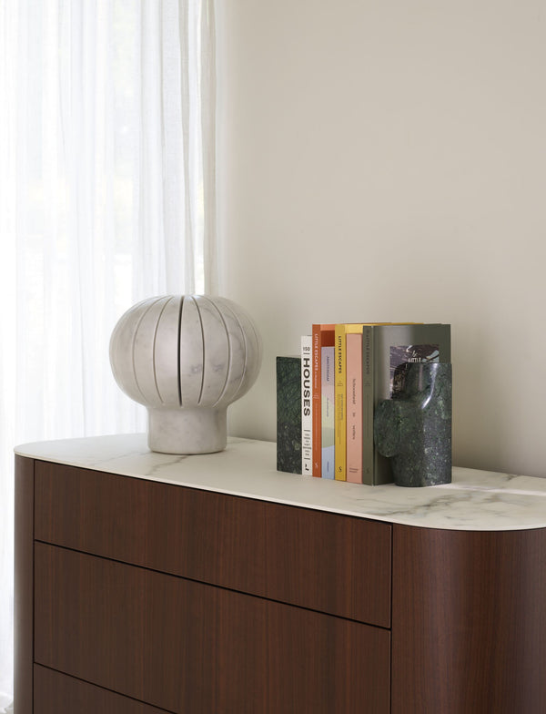 Eki — lampa na komodzie w minimalistycznym wnętrzu, obok książek, naturalne światło