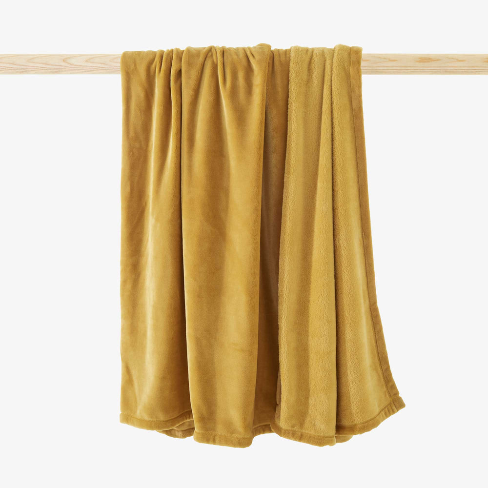 Pled Cent pour cent — Ligne Roset, tkanina w kolorze curry, widok rozłożony na drewnianym drążku