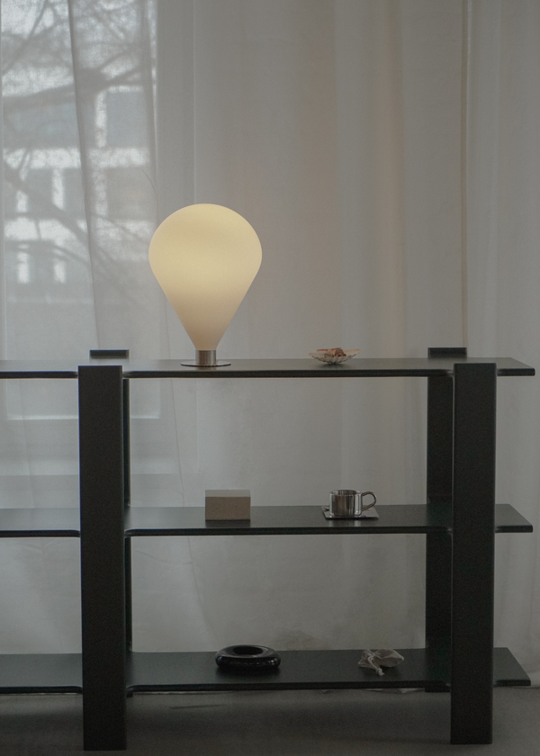 Ely — na czarnej półce przy oknie, lampa włączona, ujęcie lifestyle
