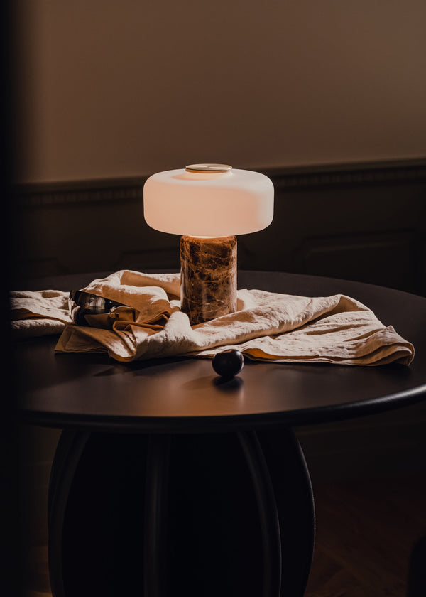 Fonte — lampa na czarnym stoliku, abażur oświetlony, marmurowa podstawa, zbliżenie