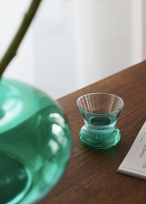 Orio Green — szklanka na drewnianym stole, ujęcie lifestyle z dekoracją