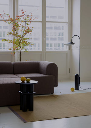 Tori — sofa w kolorze antracyt, ujęcie lifestyle z stolikiem i rośliną przy oknie