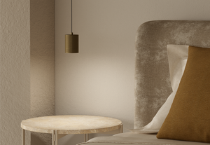 Tera — lampa w aranżacji salonu, cylindryczny klosz mosiężny nad stolikiem, ujęcie lifestyle