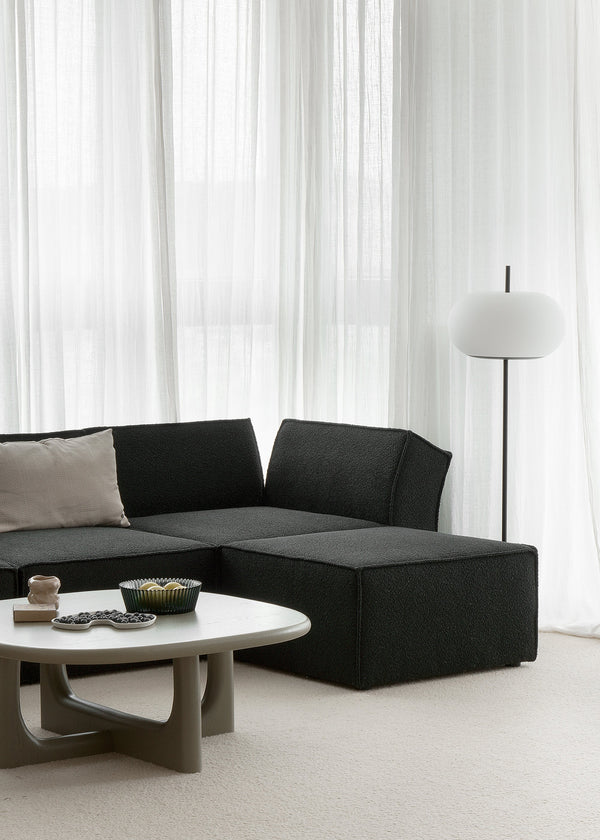 Ando — sofa narożna w wersji ciemnej tkaniny, aranżacja lifestyle z stolikiem