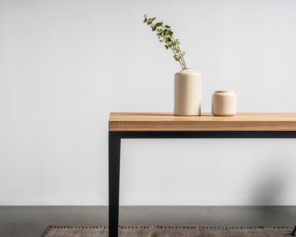 Stół Alex — blat drewniany z czarną podstawą, widok boczny, dekoracja ceramicznymi wazonami